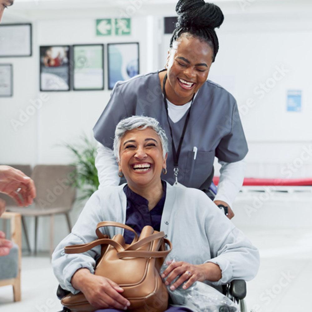 Person in a wheelchair laughing with a nurse during cancer treatment support