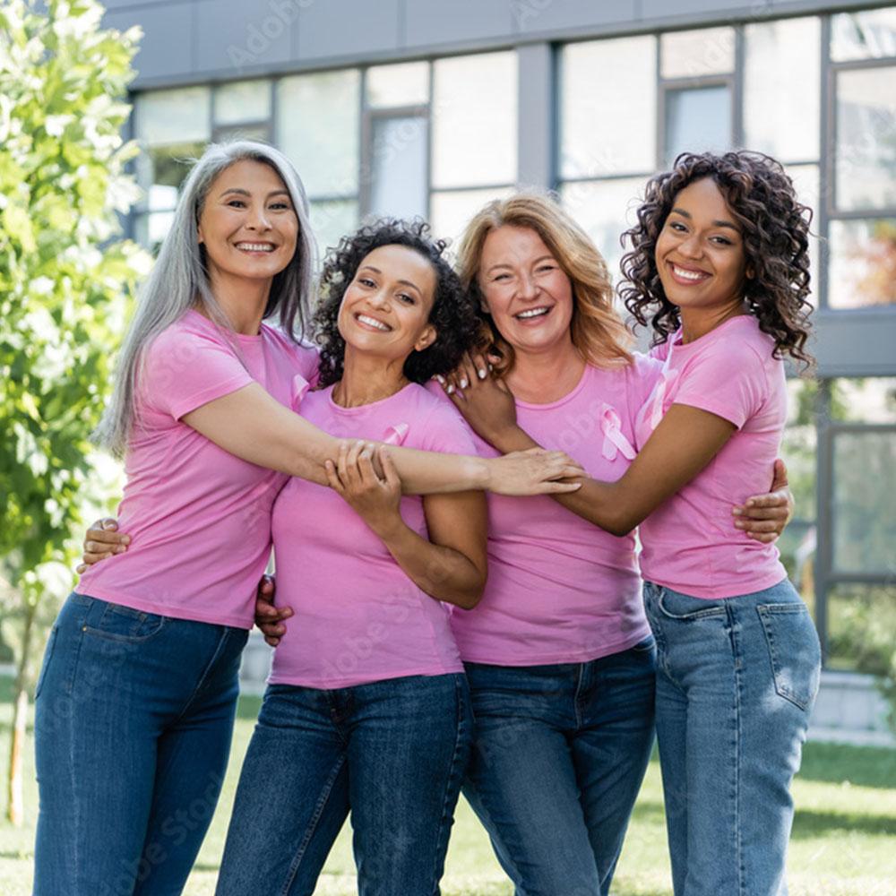 Four women in pink shirts embracing and smiling
